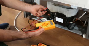 Refrigerator repair technician testing compressor wiring with a multimeter during diagnostic service.